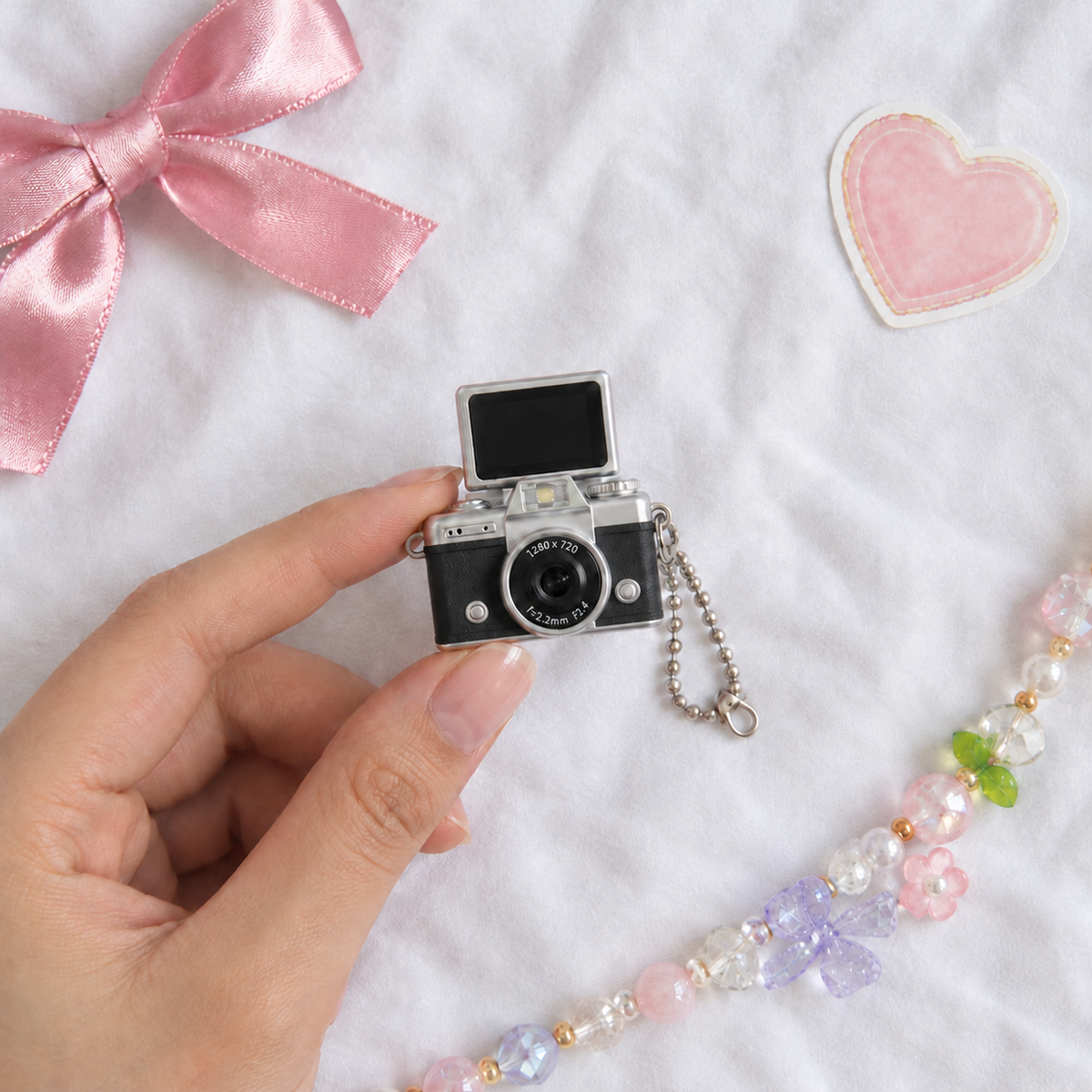 Mini Flip Screen Keychain Camera in Black, held between thumb and finger for size
