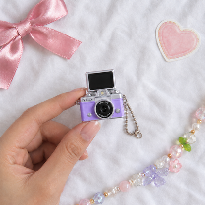 Mini Flip Screen Keychain Camera in Purple, held between thumb and finger for size