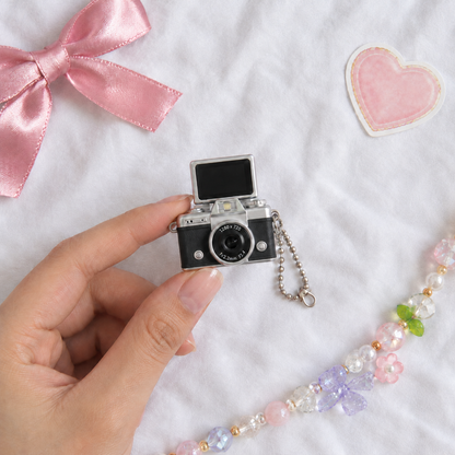 Mini Flip Screen Keychain Camera in Black, held between thumb and finger for size