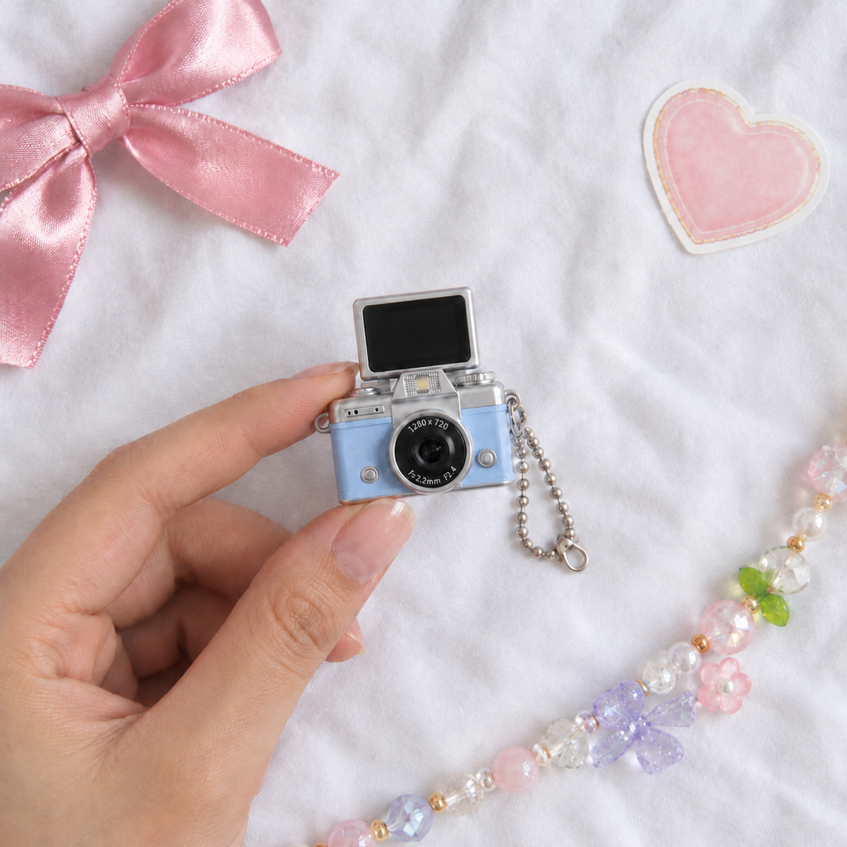 Mini Flip Screen Keychain Camera in Blue, held between thumb and finger for size